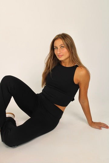 Legging deportivo acampanado Aurora negro y top deportivo Odette cruzado para mujer – posicion en el suelo sentada mirada delante – Etereo House